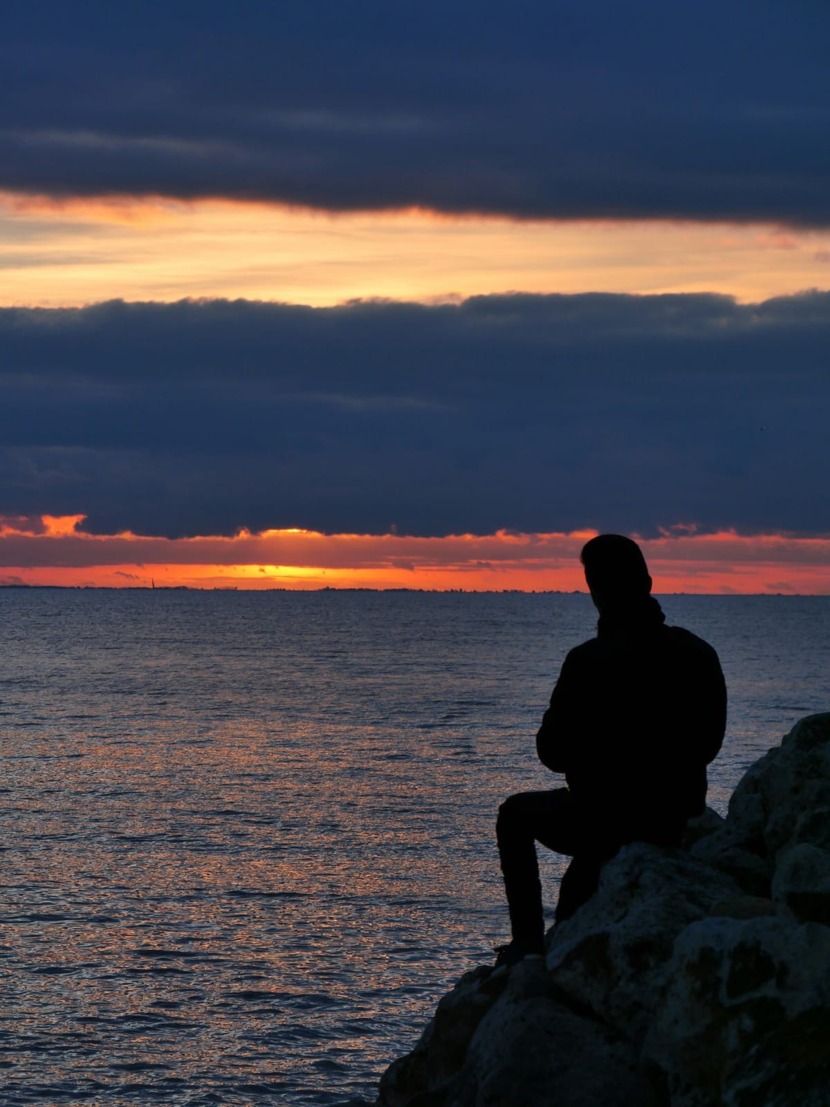 夕暮れの海を見つめる男のシルエット